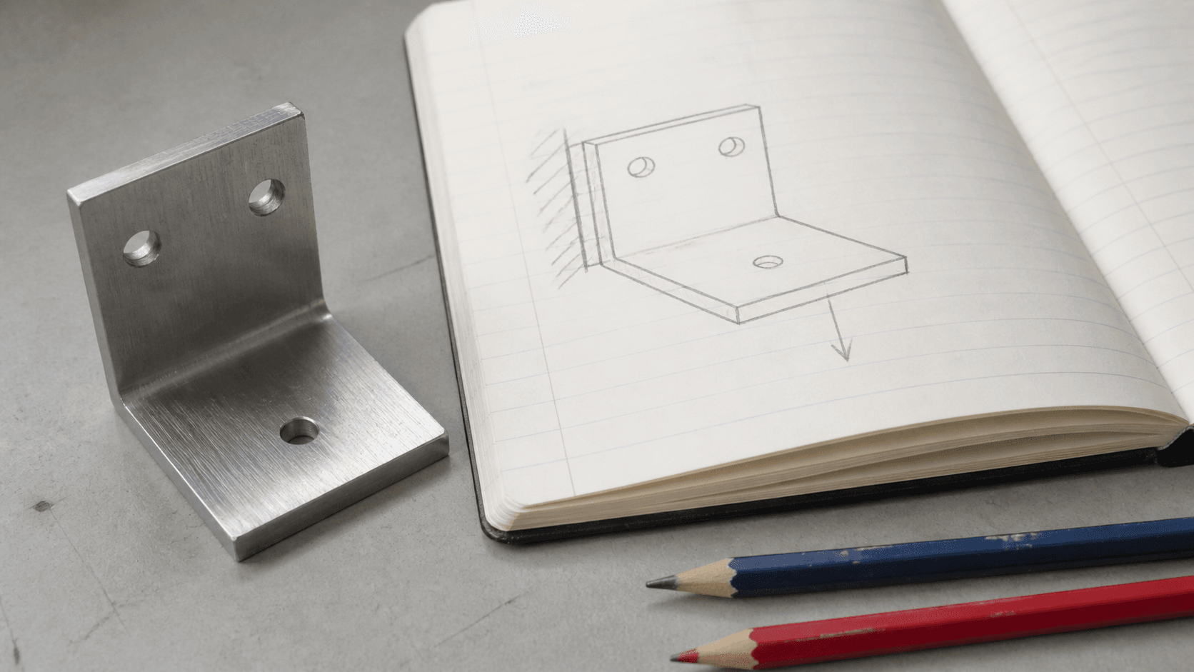 Escuadra metálica sobre un cuaderno con un croquis conceptual de apoyo y carga y dos lápices