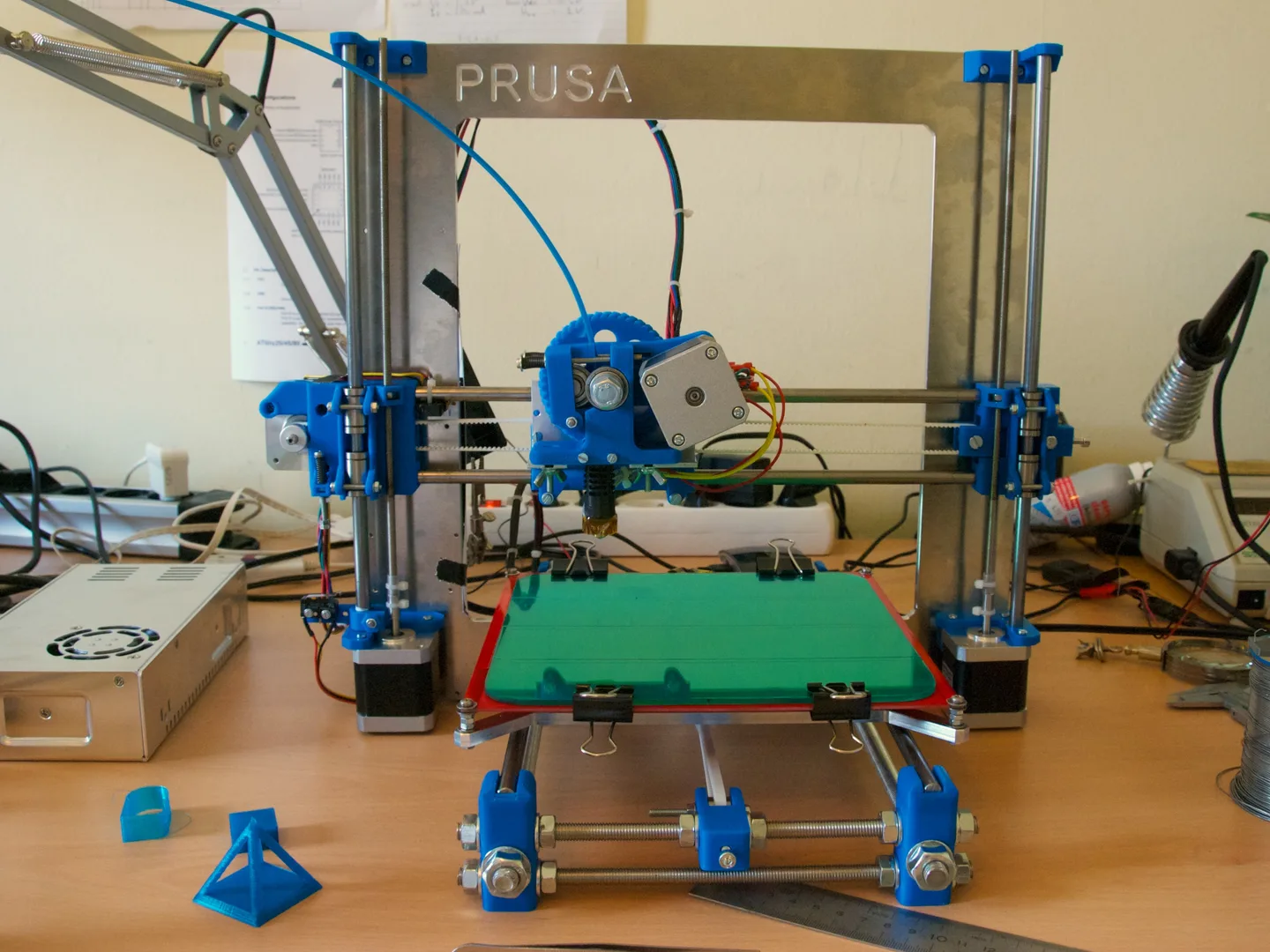 Impresora Prusa i3 de estructura abierta con extrusor y cama movil visibles.